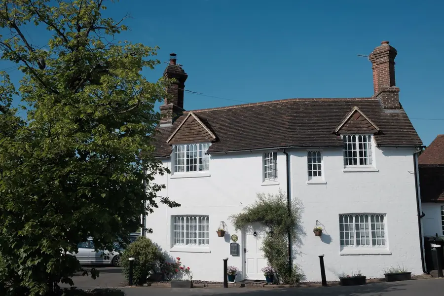 White-painted cottage with a clay tile roof, two dormers and brick chimney stacks